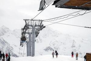 parque nacional elbrus, rússia - 13 de outubro de 2022. paisagem montanhosa nevada com oprahs, cabines de teleférico alpino e turistas. foto