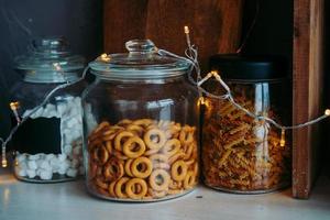 prateleira com lanches na cozinha. prateleira de mercearia em potes de vidro. prateleira com secadores e marshmallows com uma guirlanda de natal. elementos interiores com uma guirlanda foto