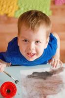 retrato de um menino de cabelos loiros, pintando um quadro. parto precoce. criatividade desde a infância.