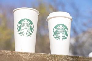 marinette, wi, eua - 10 de novembro de 2022- xícaras de café quente starbucks colocadas na neve branca no jardim de inverno, bebida fresca e quente para levar conceito. starbucks cafe coffee shop. foto