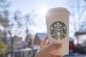 marinette, wi, eua - 14 de novembro de 2019- xícaras de café quente starbucks colocadas na neve branca no jardim de inverno, bebida fresca e quente para levar o conceito. starbucks cafe coffee shop. foto