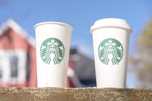 marinette, wi, eua - 14 de novembro de 2019- xícaras de café quente starbucks colocadas na neve branca no jardim de inverno, bebida fresca e quente para levar o conceito. starbucks cafe coffee shop. foto