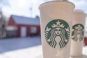 marinette, wi, eua - 14 de novembro de 2019- xícaras de café quente starbucks colocadas na neve branca no jardim de inverno, bebida fresca e quente para levar o conceito. starbucks cafe coffee shop. foto