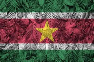 bandeira do suriname retratada em muitas folhas de palmeiras monstera. pano de fundo na moda foto