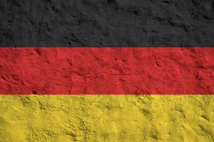 bandeira da alemanha retratada em cores de tinta brilhantes na parede de reboco em relevo antigo. banner texturizado em fundo áspero foto