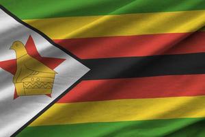 bandeira do zimbabwe com grandes dobras acenando de perto sob a luz do estúdio dentro de casa. os símbolos oficiais e cores no banner foto