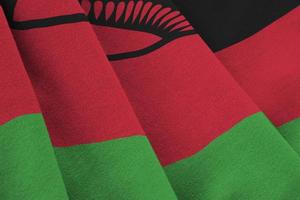 bandeira do malawi com grandes dobras acenando de perto sob a luz do estúdio dentro de casa. os símbolos oficiais e cores no banner foto