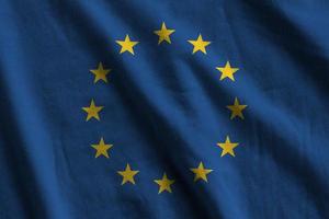 bandeira da união europeia com grandes dobras acenando de perto sob a luz do estúdio dentro de casa. os símbolos oficiais e cores no banner foto