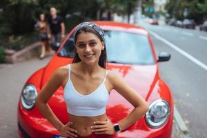 retrato de mulher bonita caucasiana em pé contra o novo carro vermelho foto