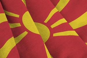 bandeira da macedônia com grandes dobras acenando de perto sob a luz do estúdio dentro de casa. os símbolos oficiais e cores no banner foto