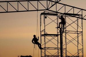 masculino trabalhando rapel em um trabalhador de silhueta de canteiro de obras foto