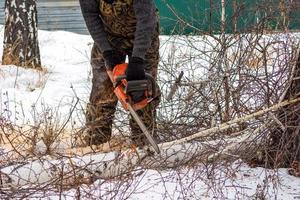 close-up de um lenhador serrando uma árvore com uma serra elétrica no inverno. 18 de janeiro de 2020, chelyabinsk, rússia foto