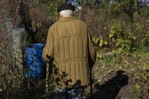 velho no barril de água. velho na rússia. homem em jaqueta militar do século 20. foto