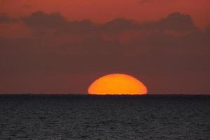 disco solar subindo no horizonte do mar, nascer do sol, amanhecer foto