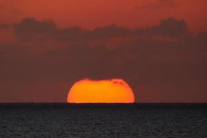 disco solar subindo no horizonte do mar, nascer do sol, amanhecer foto