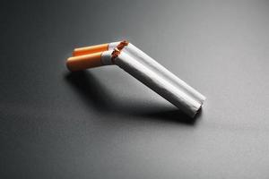 dois cigarros na forma de uma espingarda de cano duplo em um fundo preto com espaço de cópia. Pare de fumar. o conceito de fumar mata. foto