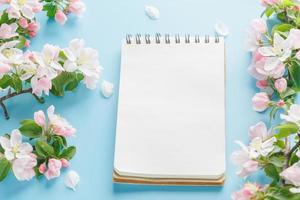 sakura de primavera florescendo em um fundo azul com espaço de bloco de notas para uma mensagem de saudação. o conceito de primavera e dia das mães. lindas flores delicadas de cerejeira rosa na primavera foto