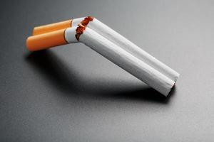 dois cigarros na forma de uma espingarda de cano duplo em um fundo preto com espaço de cópia. Pare de fumar. o conceito de fumar mata. foto