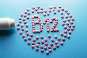 comprimidos rosa na forma de b12 no coração sobre um fundo azul, derramados de uma lata branca. foto