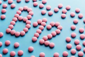 pílulas cor de rosa na forma da letra b12 em um fundo azul, derramadas de uma lata branca. foto