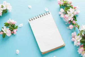 sakura de primavera florescendo em um fundo azul com espaço de bloco de notas para uma mensagem de saudação. o conceito de primavera e dia das mães. lindas flores delicadas de cerejeira rosa na primavera foto