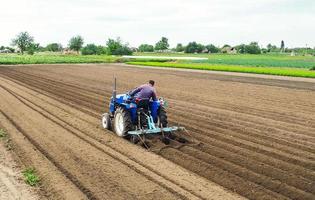 um agricultor em um trator ara o campo para posterior semeadura da colheita. preparo do solo. trabalhando com um arado. cultivo de plantas de alimentos vegetais. agronegócio agrícola. indústria agrícola. foto