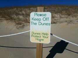 por favor, evite o sinal das dunas com areia e plantas foto