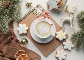 uma xícara de café com leite, biscoitos caseiros e bolas de natal e suéter de malha. foto