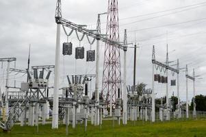 linha de transmissão de metal com os componentes da rede elétrica, o sistema de equipamentos de energia para a transmissão de eletricidade, corrente elétrica com o transformador na usina foto