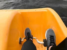 pernas em botas de tênis esporte cinza pedal em um catamarã amarelo foto