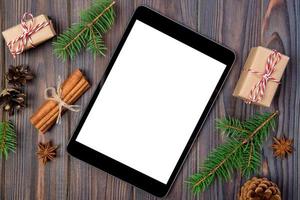 tablet digital simulado com decorações rústicas de fundo de madeira de natal para apresentação de aplicativos. vista superior com espaço de cópia foto