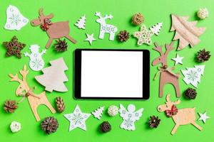 fundo verde de natal com brinquedos e decorações de férias. vista superior do tablet digital. feliz ano novo conceito foto