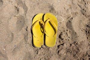 chinelos de praia amarelos na praia, verão, banho foto