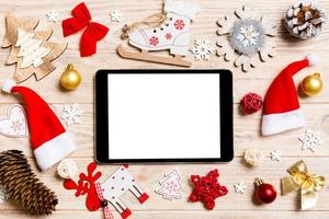 vista superior do tablet em fundo de madeira de férias. decorações de ano novo e brinquedos. conceito de natal foto