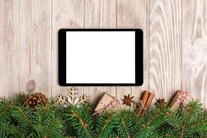 tablet digital simulado com decorações rústicas de fundo de madeira de natal para apresentação de aplicativos. vista superior com espaço de cópia foto