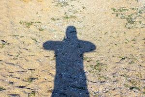 sombra do homem viajante com mochila tirar foto na praia de areia na hora do pôr do sol, viajar