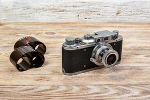 câmera velha e tira de filme em branco na mesa de madeira foto