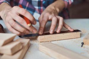mãos de carpinteiro medindo com um lápis de prancha de madeira. foto