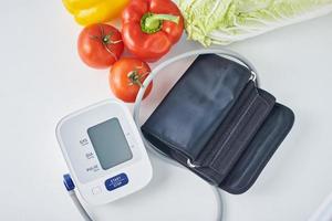 monitor de pressão arterial digital e legumes frescos foto
