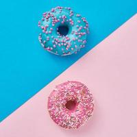 dois donuts em um fundo rosa pastel e azul. foto