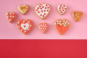 biscoitos decorados em forma de coração em um fundo colorido vermelho e rosa, vista superior foto