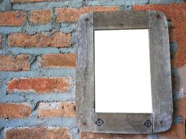 moldura de madeira rústica pendurada na parede de tijolos antigos com lugar vazio para texto ou imagem foto