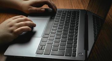 vista lateral das mãos de mulher usando laptop na mesa de madeira vintage. conceito de negócios, finanças e jogos. trabalho a partir de casa. local de trabalho. foto