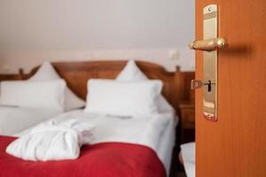 porta de madeira entreaberta com a chave de um quarto de hotel, através da qual se vê um quarto. foto
