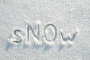 palavra neve com letras grandes não escritas em um banco de neve. o conceito do fim do inverno e a antecipação da primavera. vista do topo. foto