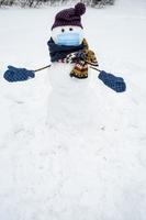 boneco de neve caseiro engraçado em uma máscara médica, chapéu, cachecol e luvas quer abraçar. foto