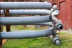 um grande cavalete de tubulação de metal de ferro com tubos e fios elétricos e equipamentos na refinaria petroquímica refinaria industrial foto