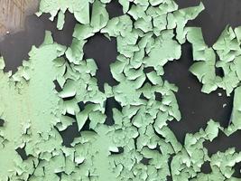 a textura da velha tinta descascada verde-clara turquesa surrada com rachaduras e arranhões na parede de metal enferrujada. fundo foto