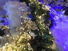 árvore de natal ao ar livre com neve, bokeh de luzes ao redor e neve caindo, atmosfera de natal foto