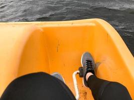 pernas em botas de tênis esporte cinza pedal em um catamarã amarelo foto